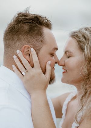 Engaged couple sharing an intimate almost-kiss moment on the beach with soft natural light.