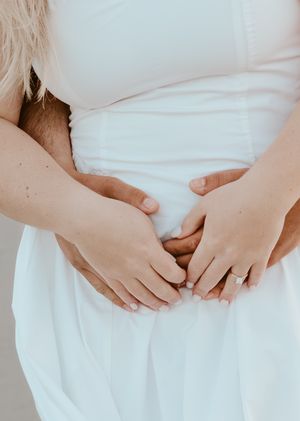 Close up of hands gently holding soft white fabric with delicate and tender gesture in natural light.