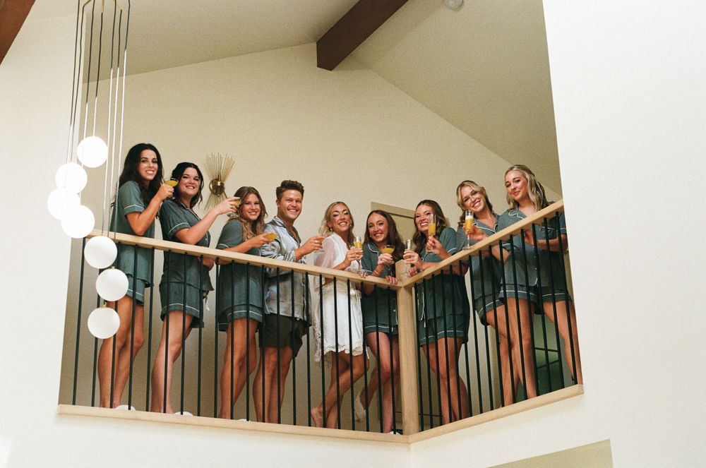 Candid moment of Dani laughing with her bridesmaids in matching robes before putting on her dress.