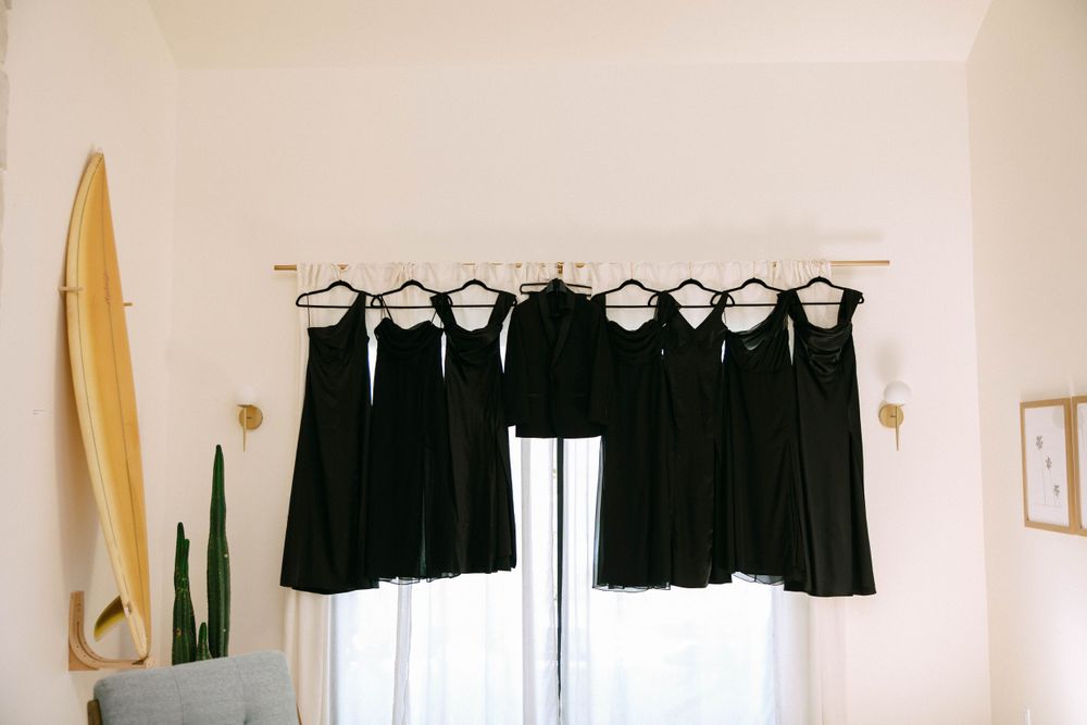 Editorial-style dress shot of Dani’s bridesmaid dresses hanging by a sunlit window in a Ventura county Airbnb.
