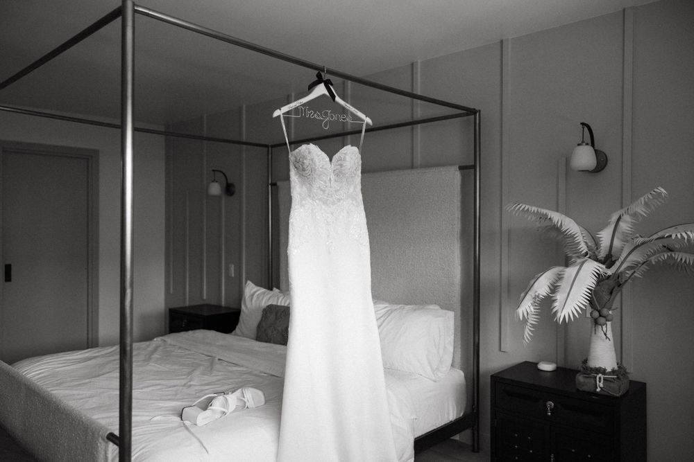 Editorial-style dress shot of Dani’s wedding dress hanging on a bed frame in a Ventura county Airbnb.