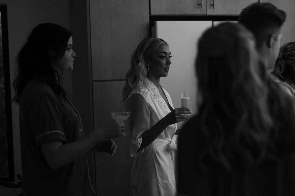 Candid moment of Dani laughing with her bridesmaids in matching robes before putting on her dress.