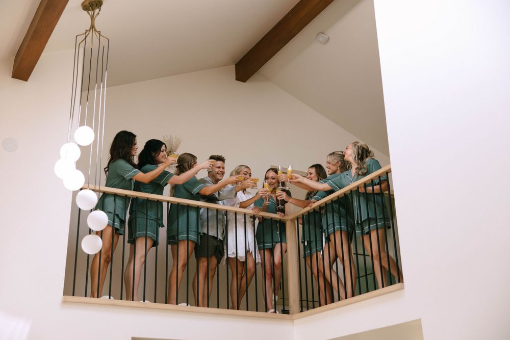 Candid moment of Dani laughing with her bridesmaids in matching robes before putting on her dress.