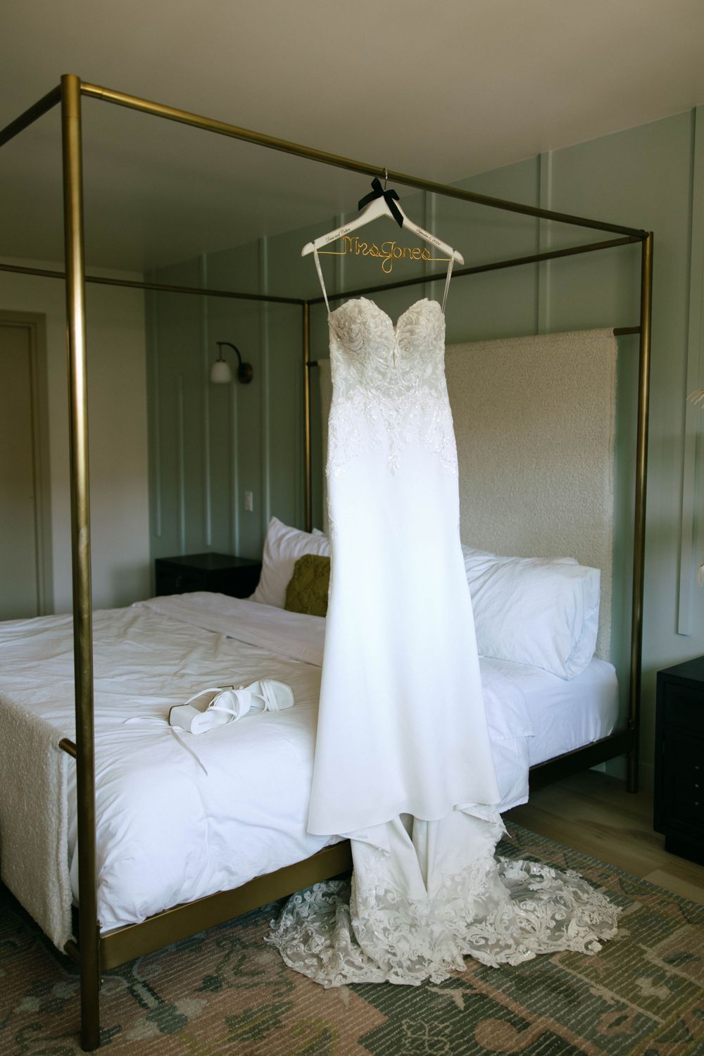 Editorial-style dress shot of Dani’s wedding dress hanging on a bed frame in a Ventura county Airbnb.