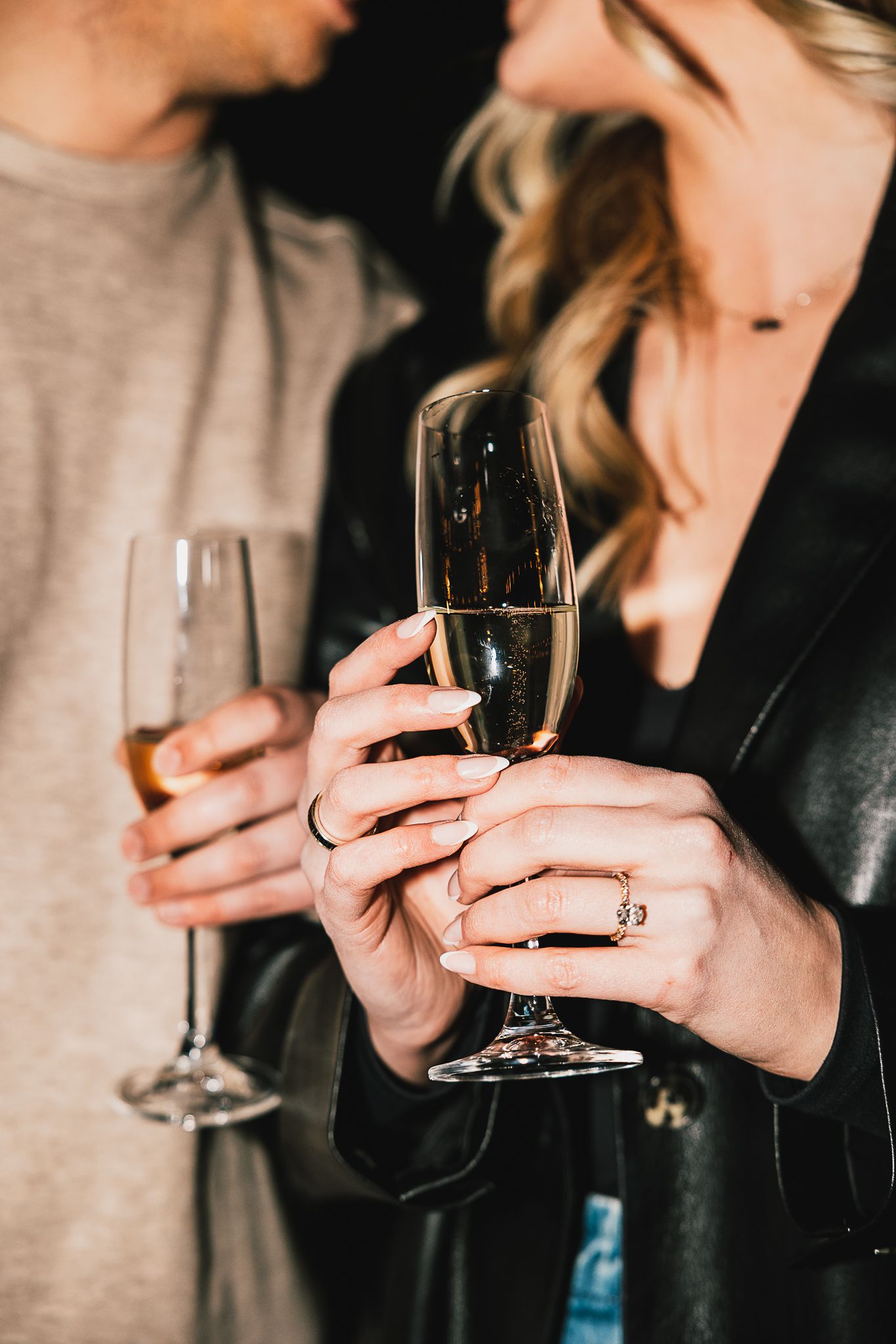 Couple celebrating with champagne flutes, woman wearing diamond ring.