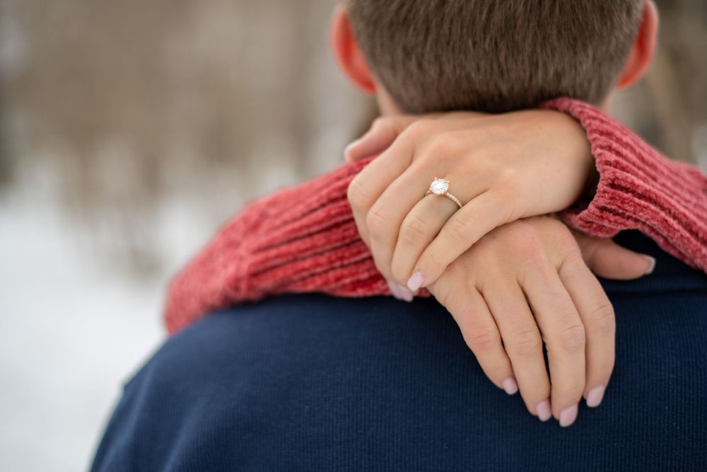 Close-up of hands showing off an engagement ring against a cozy winter sweater.