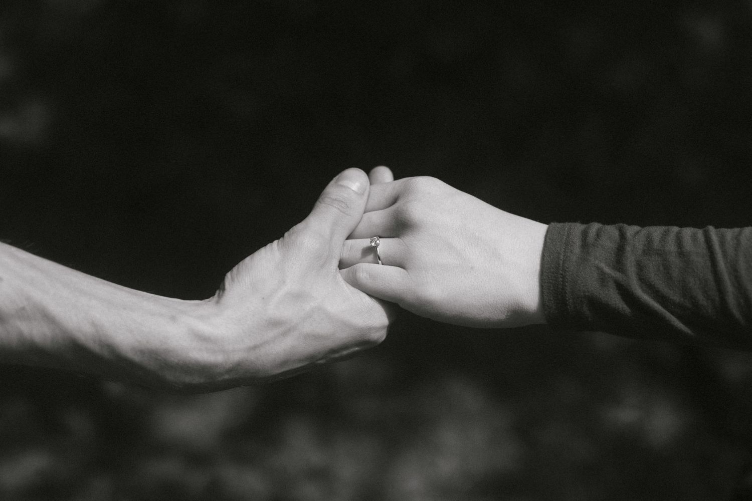 Two hands reaching towards each other against a dark background in a tender gesture of connection.