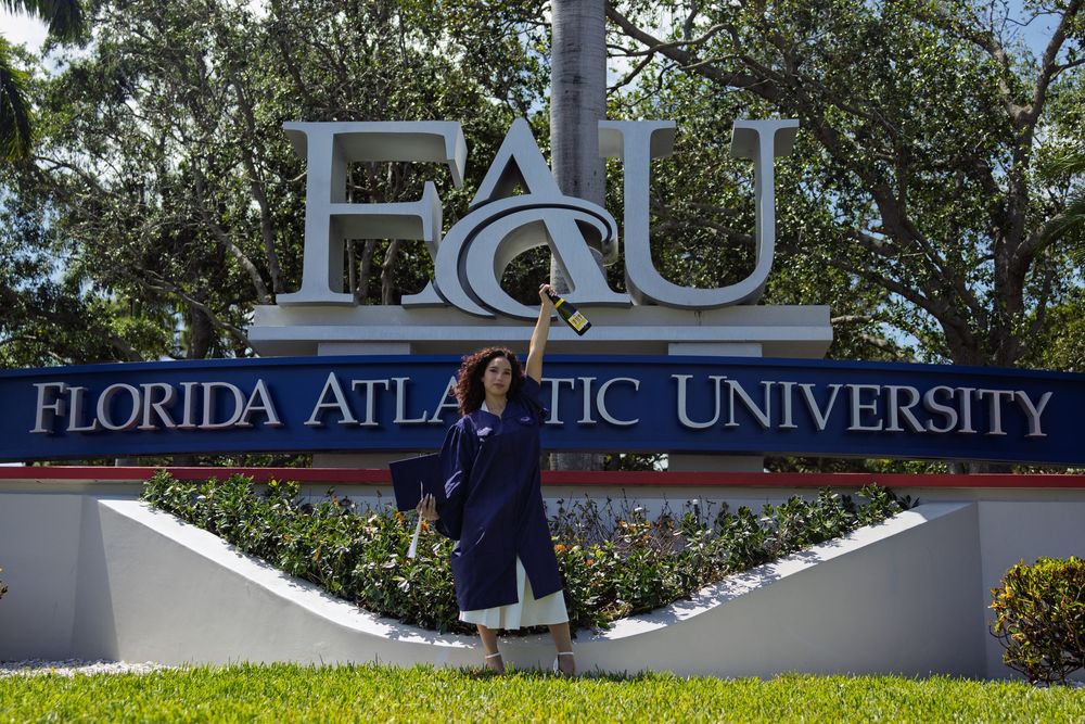 White lettering of Florida Atlantic University sign against blue sky and palm trees.
