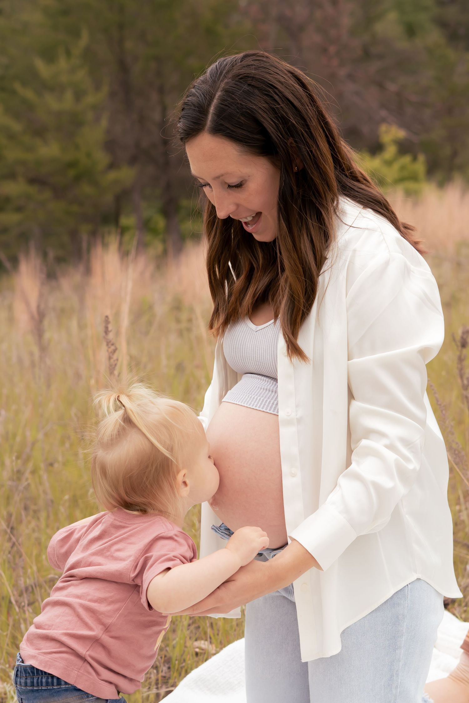 Child kissing pregnant mom's belly for maternity photos at Crow Wing State Park in Brainerd, Minnesota.
