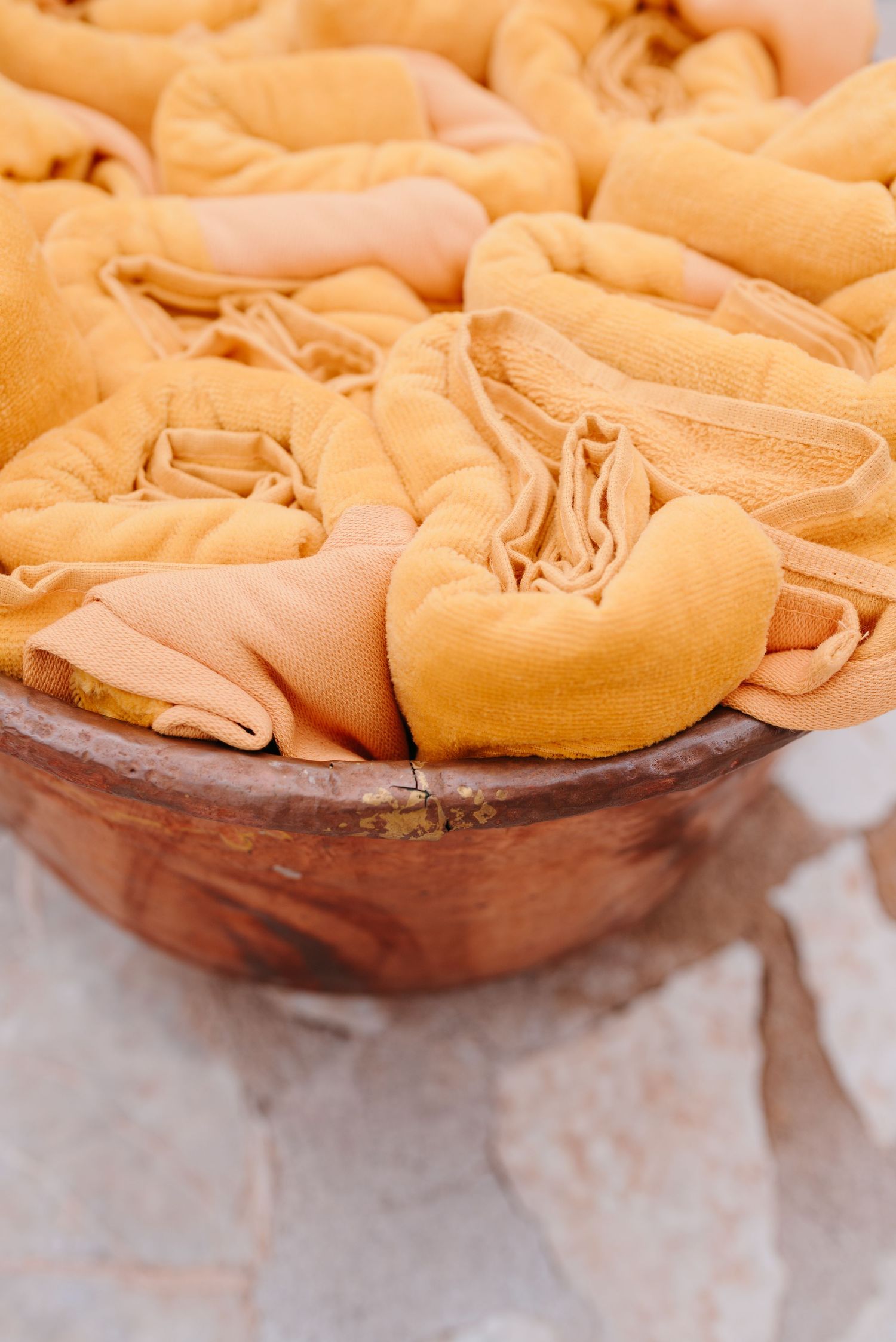 Close-up view of fresh pasta dough being rolled and formed into saffron-colored ribbons on a wooden surface.