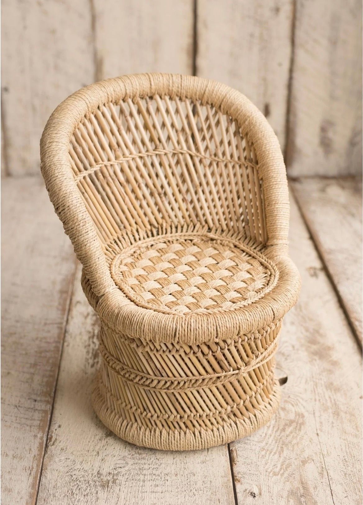 Vintage metal bucket with wooden handle sits empty on rustic wooden floorboards.