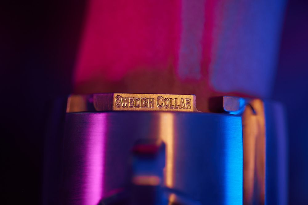 Golden speaker text on metallic surface illuminated by vivid pink and blue lighting effects.