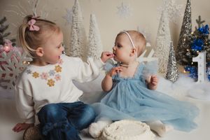 Children in winter-themed setting share cake and treats during festive holiday celebration with sparkly decorations.
