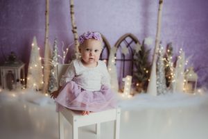 Festive holiday scene with glowing candles and decorative bottles arranged against a purple backdrop.