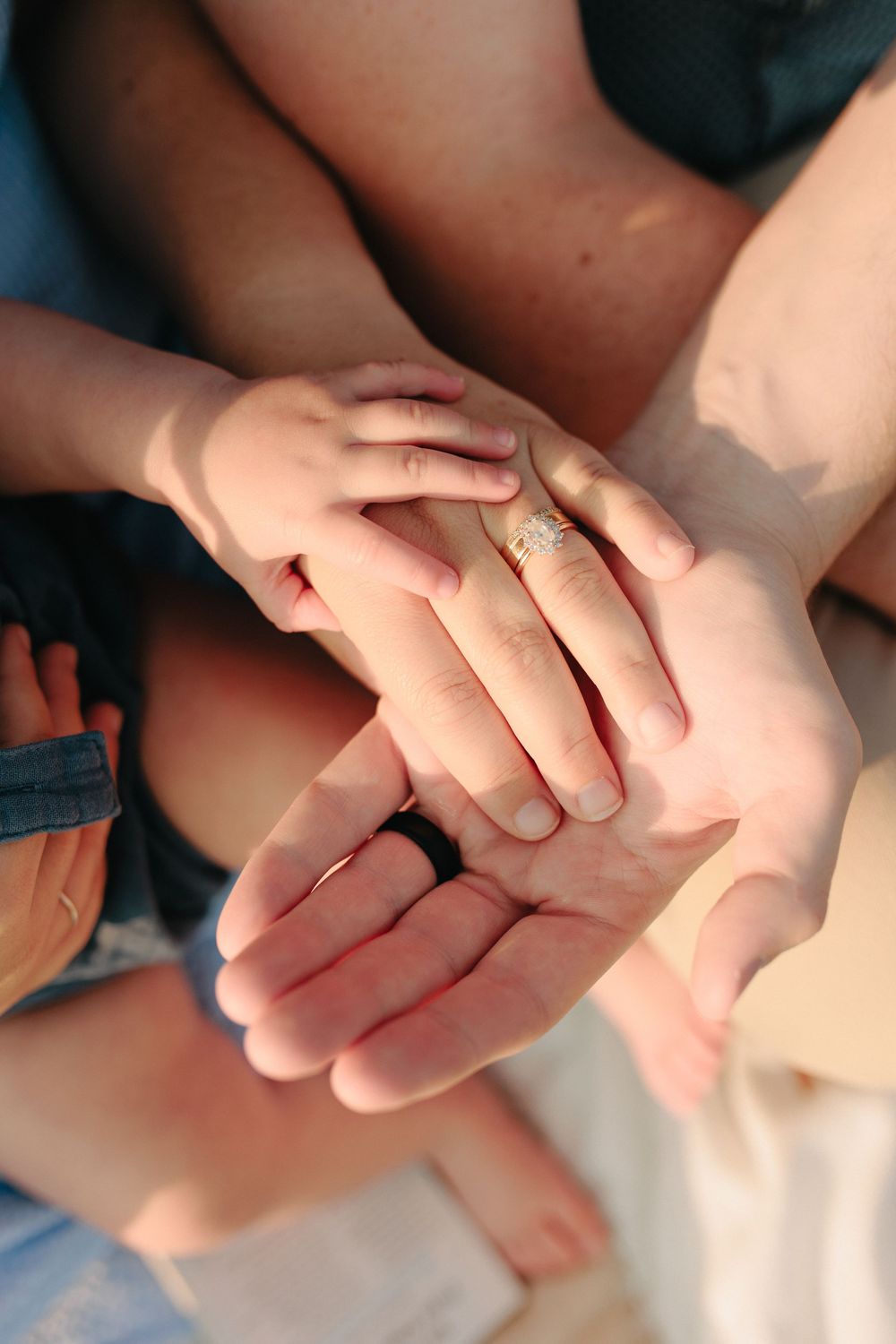 Close-up shot of hands gently stacked together showing unity and support, with one hand wearing a delicate ring.