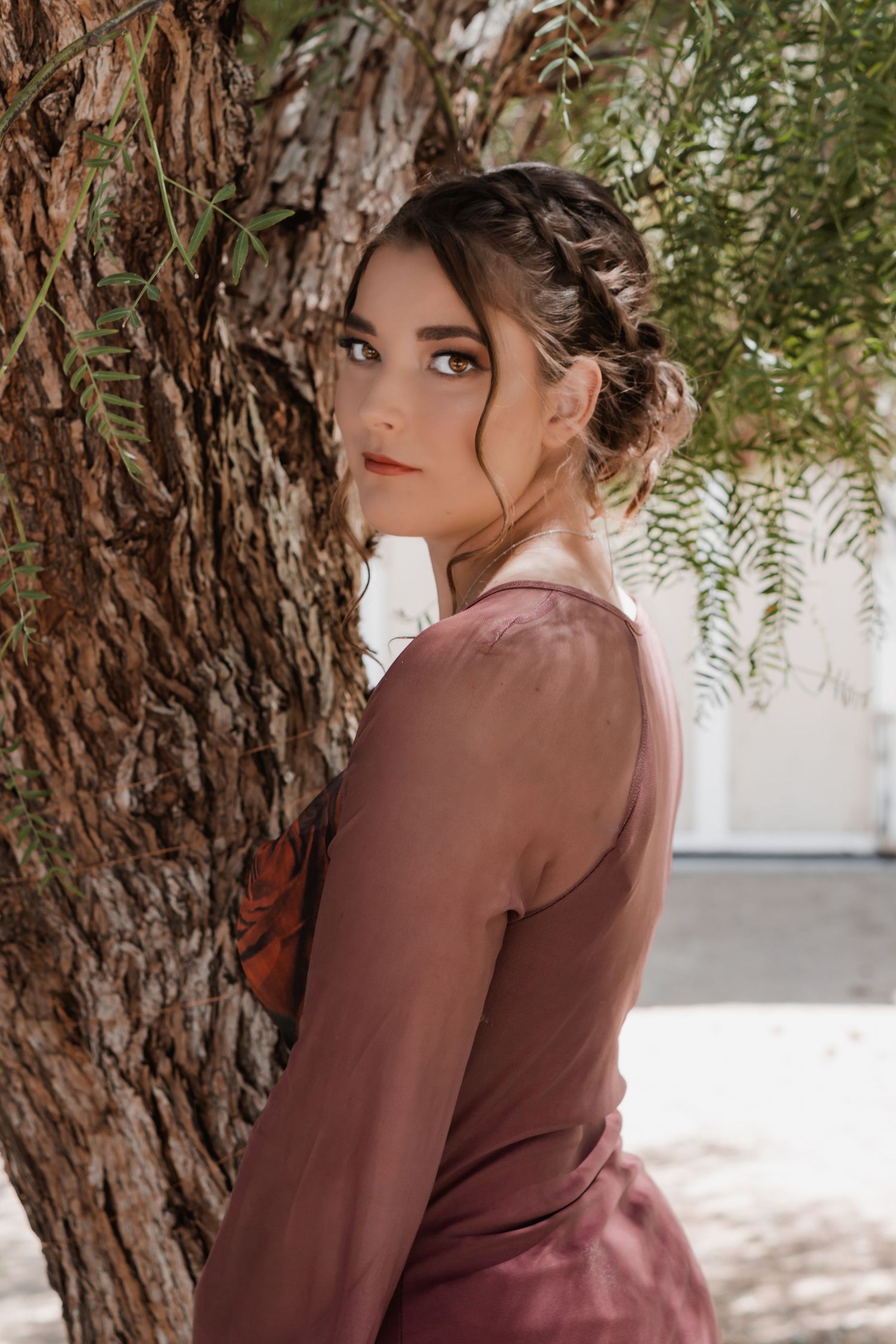 a glam portrait of a young woman standing in front of a tree.