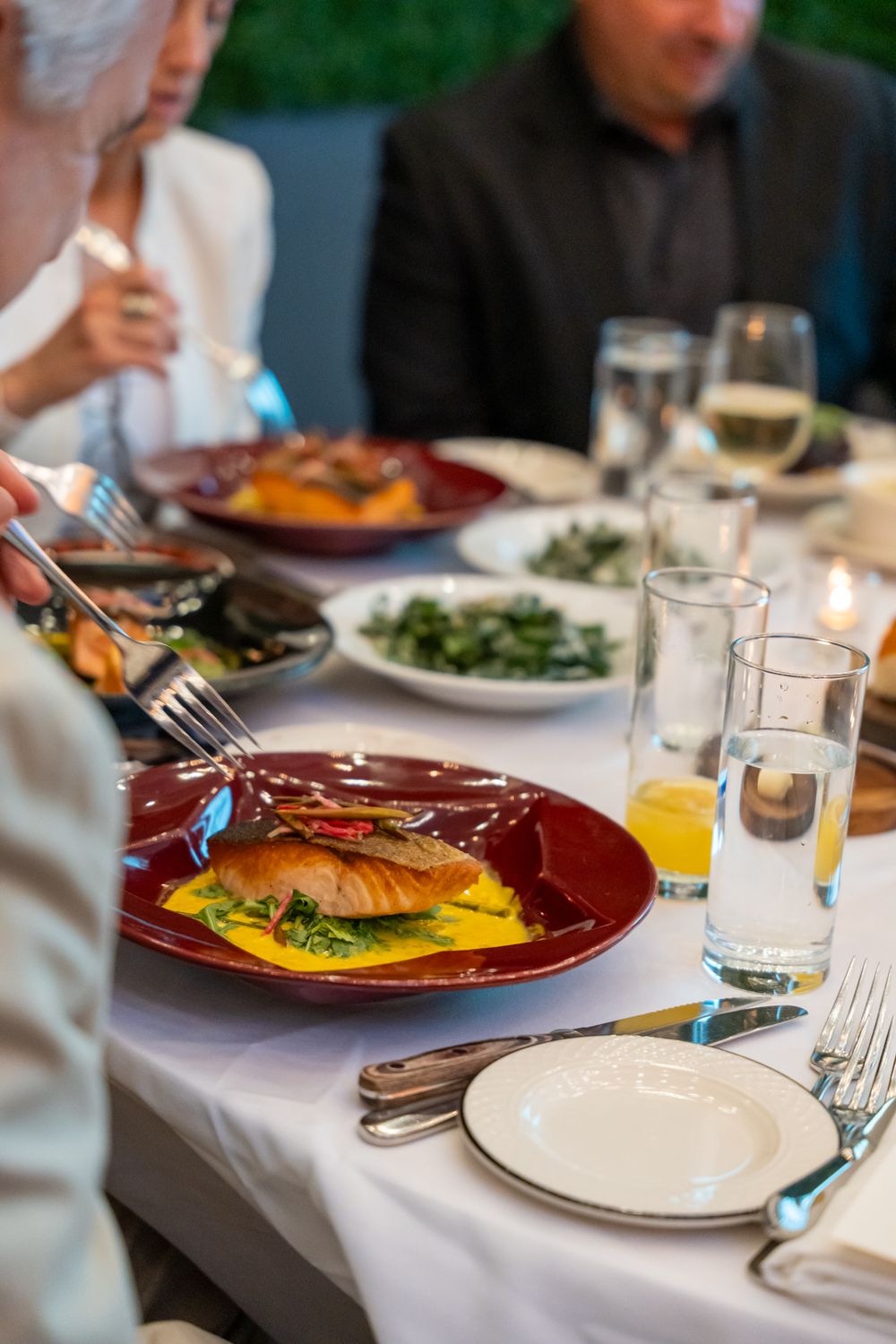 Elegant dinner table setting with plated meals and wine glasses at an upscale restaurant.