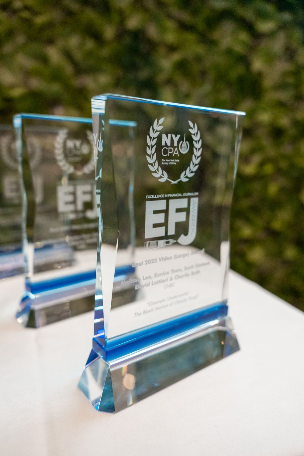 Crystal award trophies with blue bases lined up on white display table.