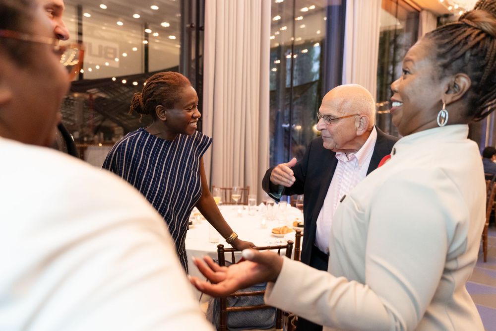 Business professionals mingling at an upscale networking event with overhead lighting.
