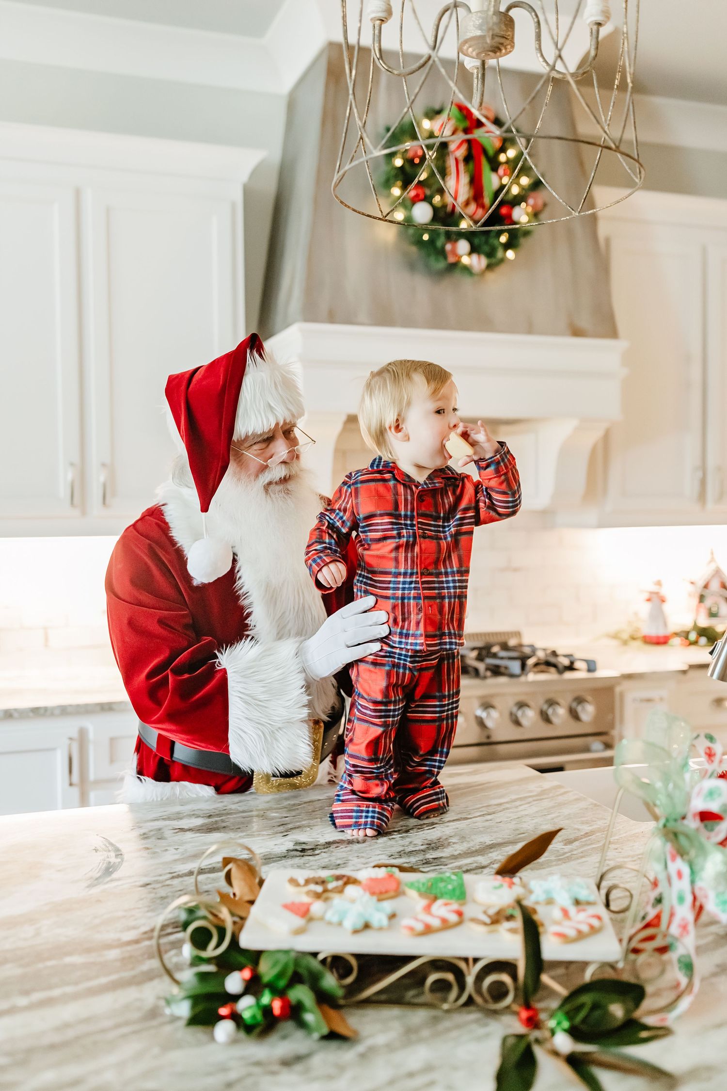 A festive holiday scene in a bright kitchen with decorative wreaths and greenery on a white marble countertop.