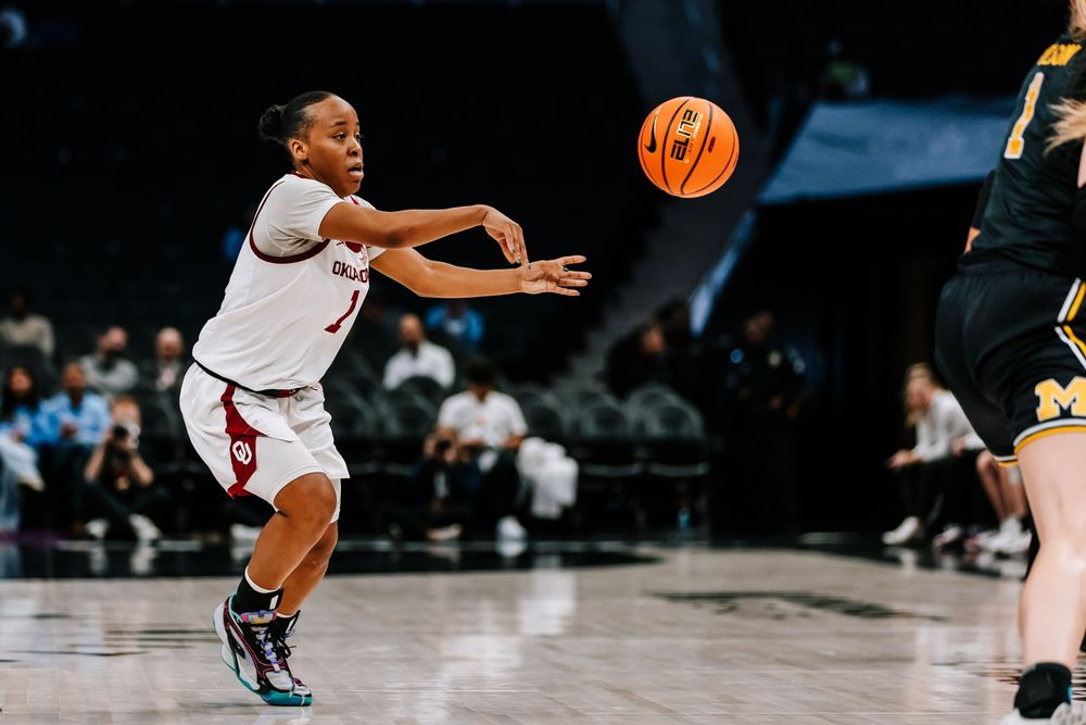 Oklahoma women's basketball player passes the ball against Michigan during a college game.
