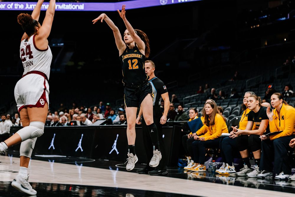 Michigan player #12 shoots a jump shot during a women's college basketball game against Oklahoma.