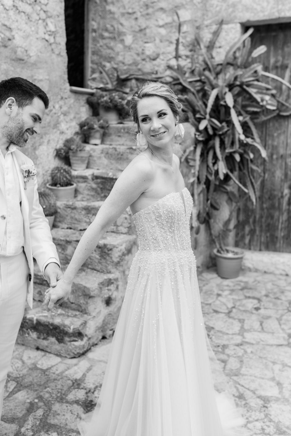 Ein Schwarz-Weiß-Foto des First Look Moments in der Finca Xiclati auf Mallorca. Die Braut dreht sich um dem Bräutigam ihr Kleid zu zeigen.