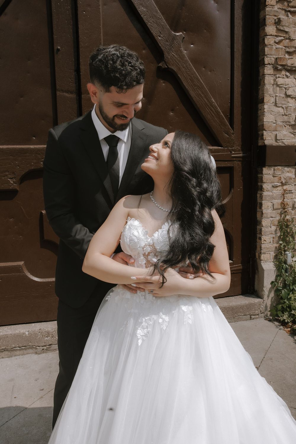 A romantic wedding couple poses against a rustic wooden door in an intimate portrait.