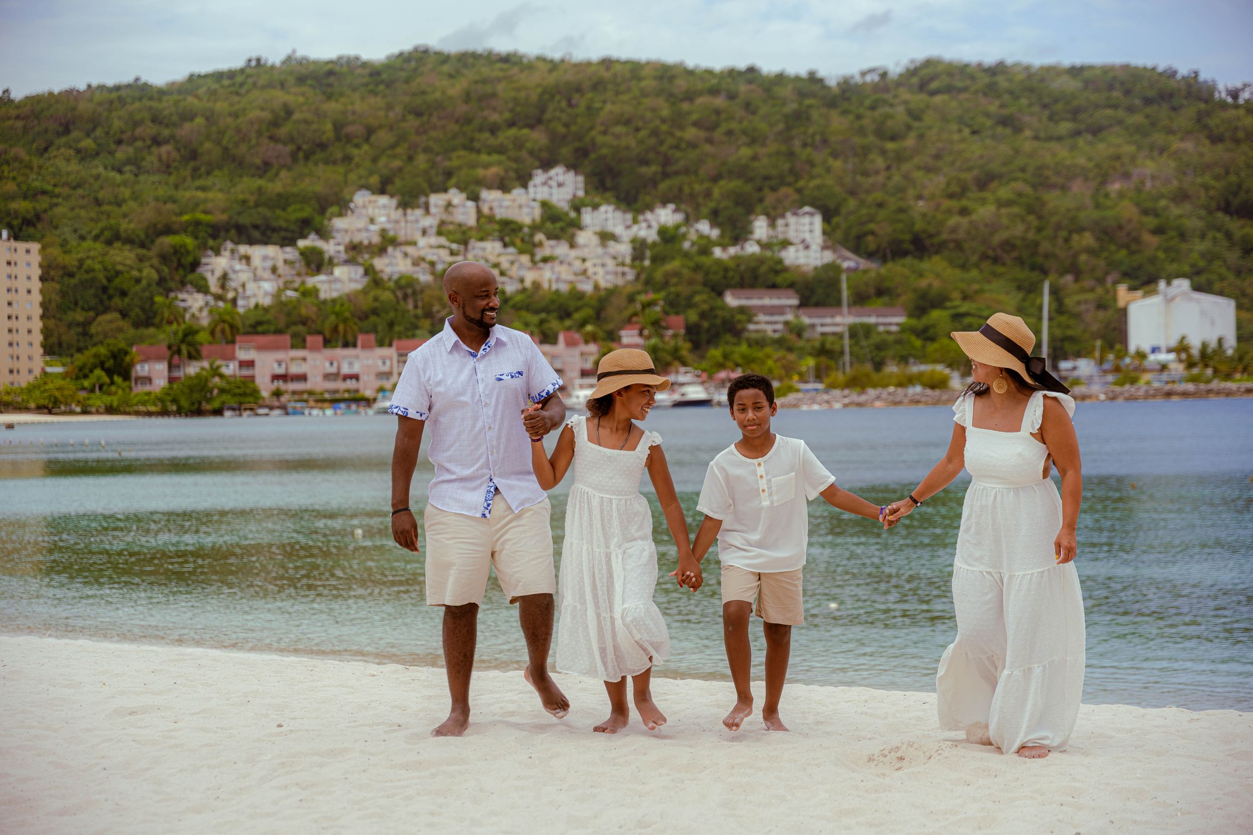 Jamaican Family Photographer Audley Green  Group enjoying a tropical beach day with turquoise water, white sand and hills in the background.