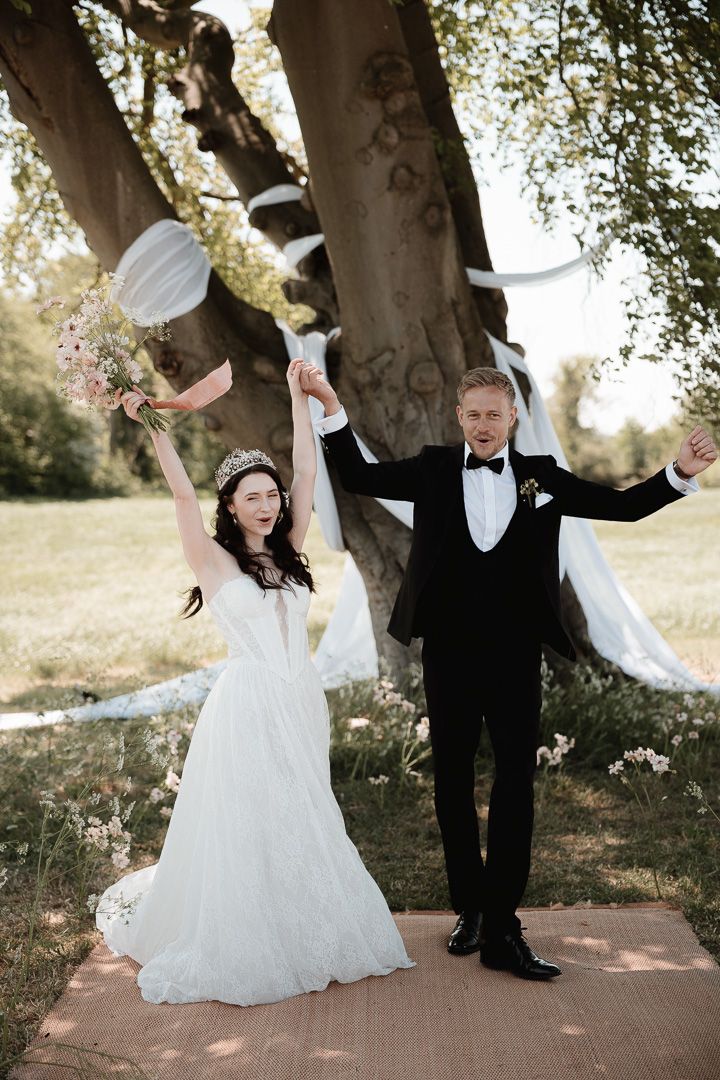 A sequence of celebratory dance poses under trees during a wedding photoshoot in formal attire.