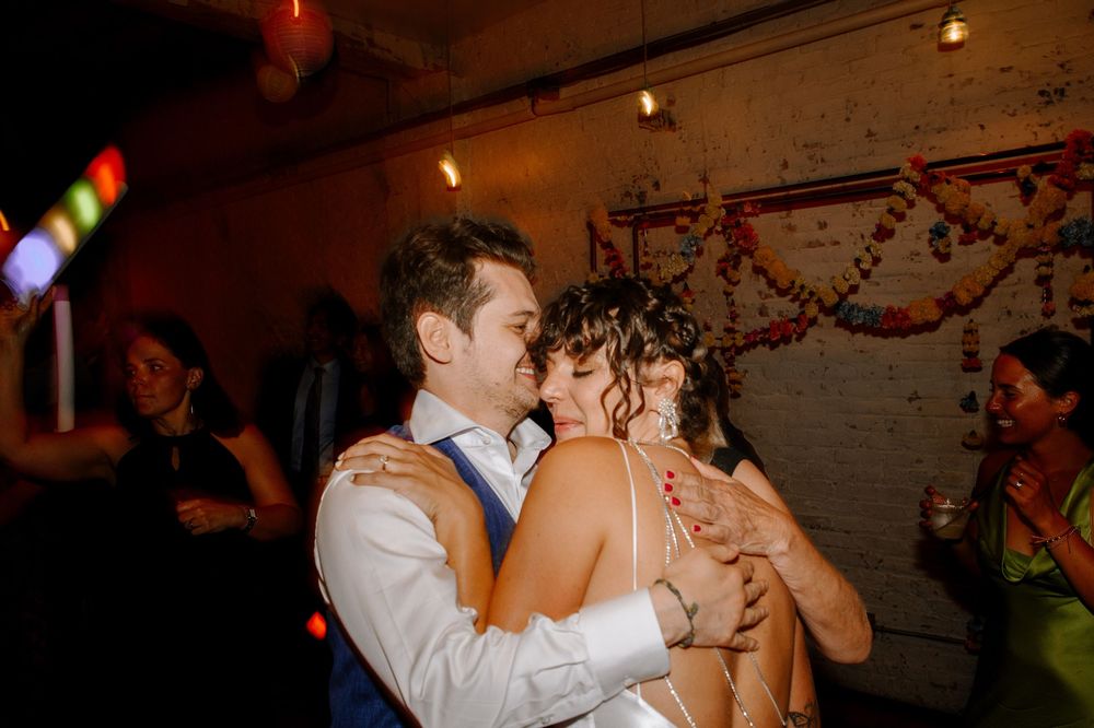 A row of dancing couples on a dimly lit dance floor with string lights and decorative branches overhead.