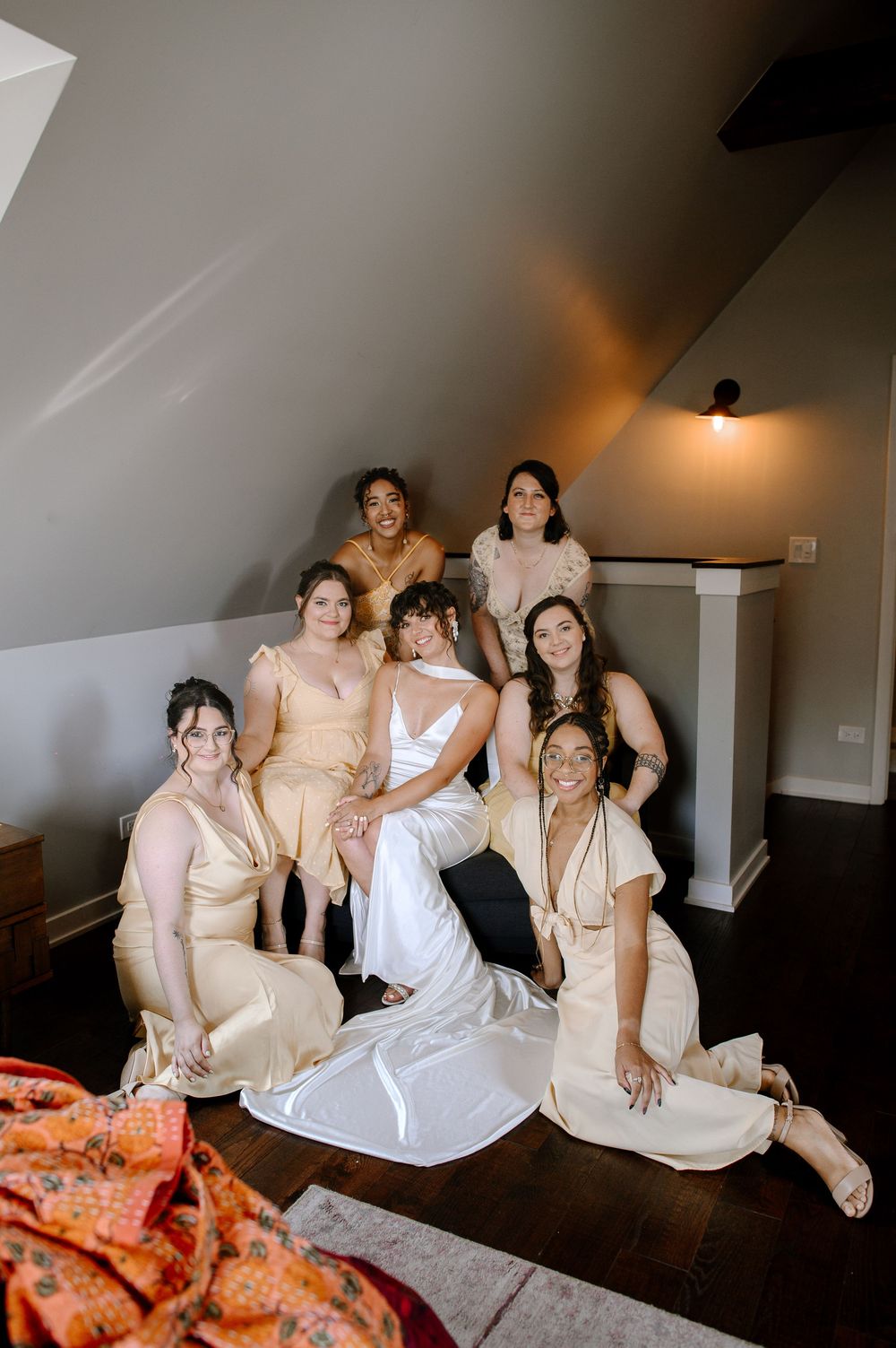 A bridal party poses together in a room, with bridesmaids wearing champagne colored dresses and the bride in white.