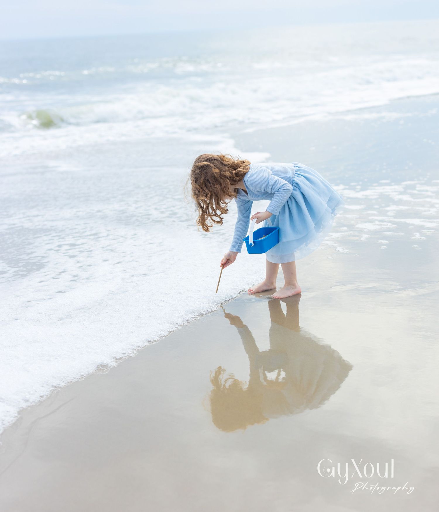 A sequence of images showing a person in a light blue dress collecting seashells along a misty beach shoreline.