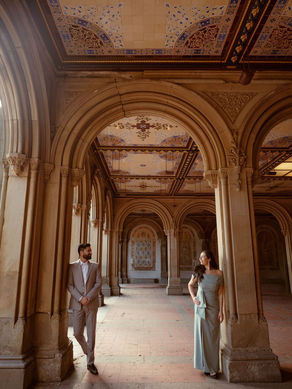 A romantic couple poses in a dreamy archway at Bethesda Terrace in Central Park during their engagement shoot.