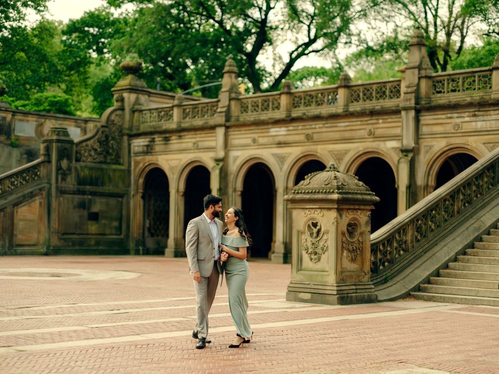 A couple shares a romantic moment at the historic Bethesda Terrace in Central Park featuring ornate stone arches and stairways.