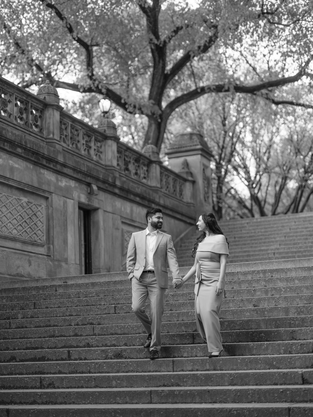 Two people in light colored outfits climb concrete steps among trees in this dramatic black and white sequence.