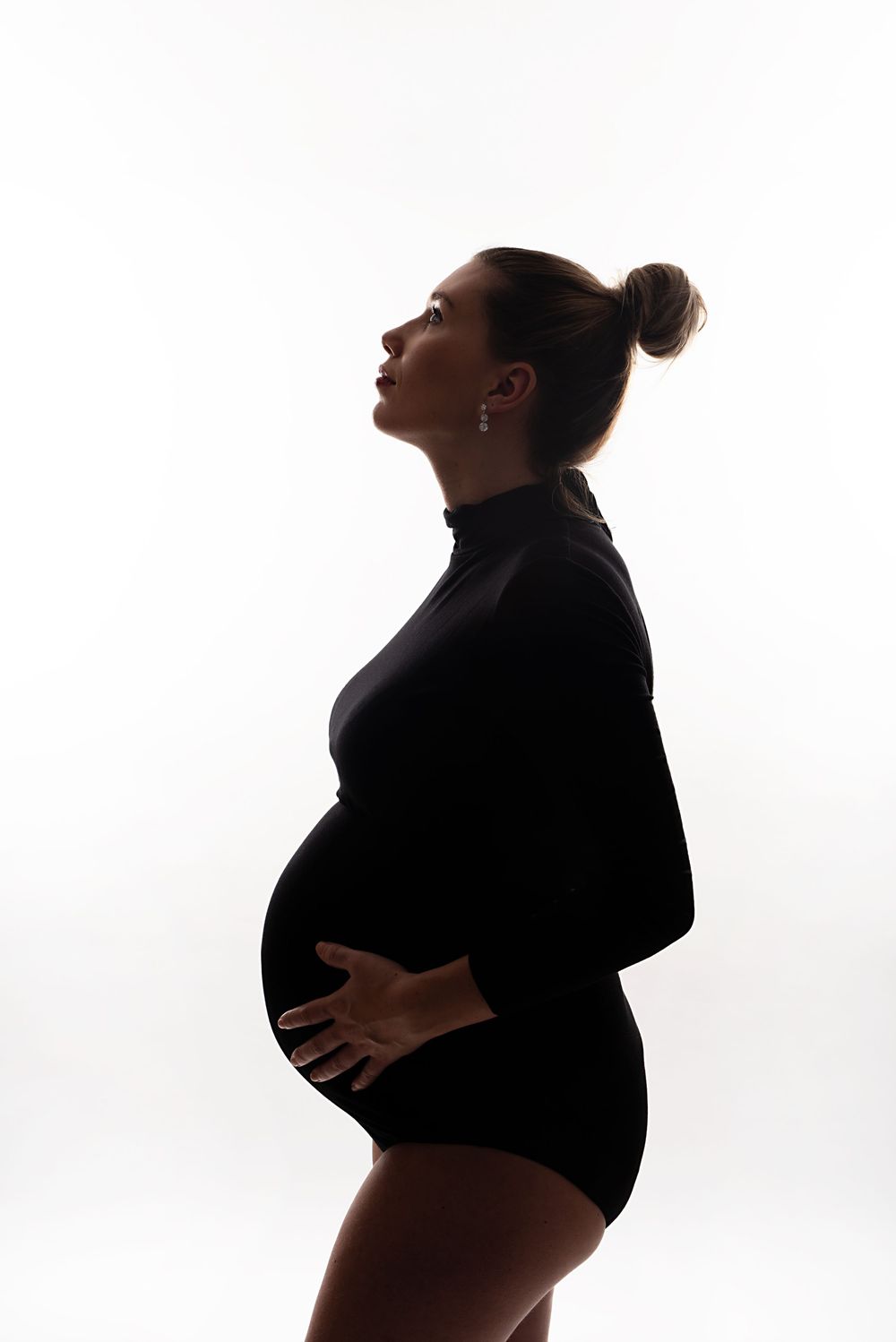 Silhouette maternity photos highlighting pregnancy curves against white backdrop.