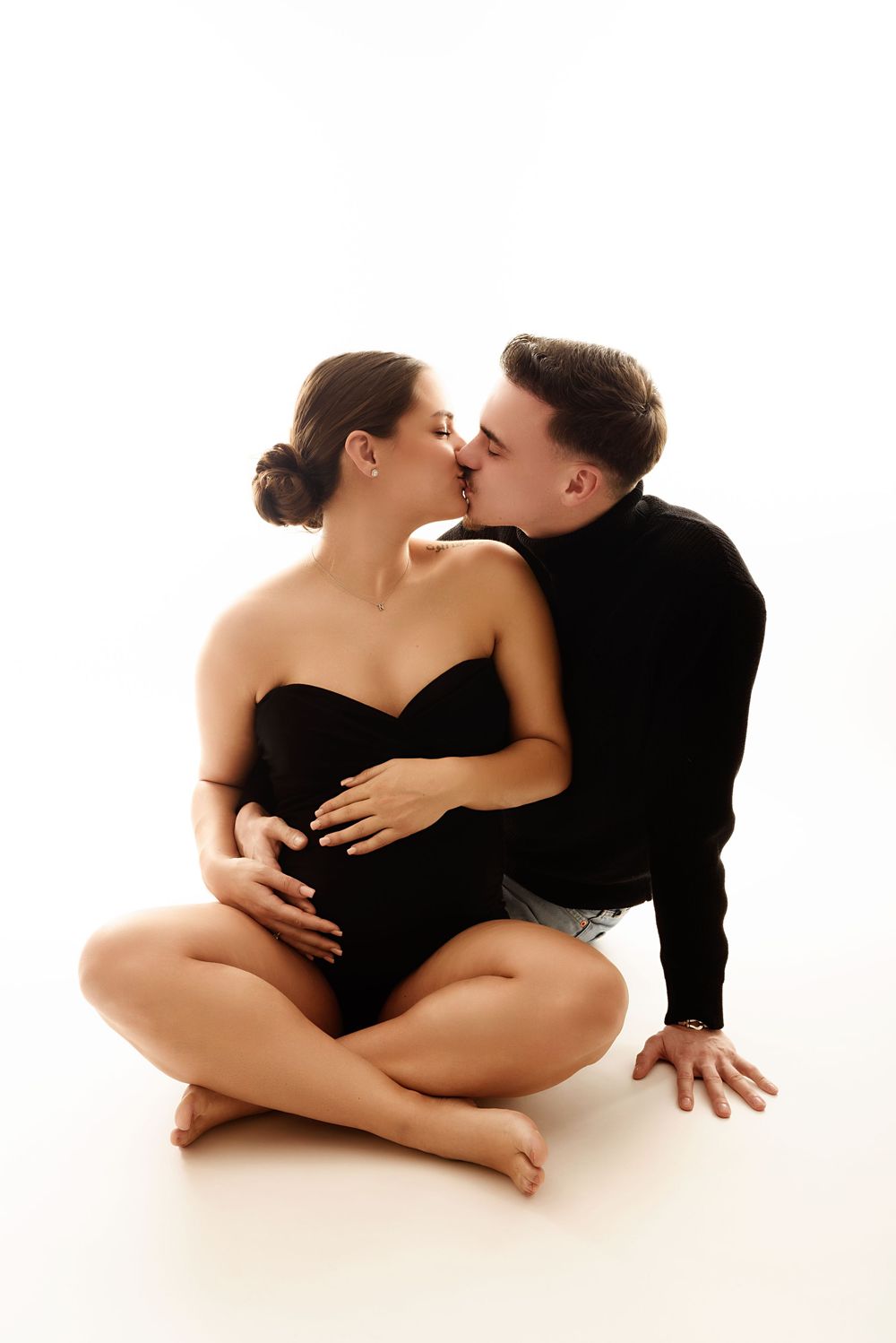 Romantic maternity photos showing tender moments between couple on white background.