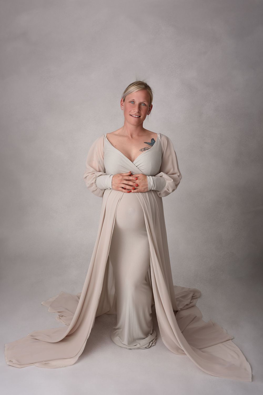 Elegant maternity portraits in cream-colored dress against neutral backdrop.