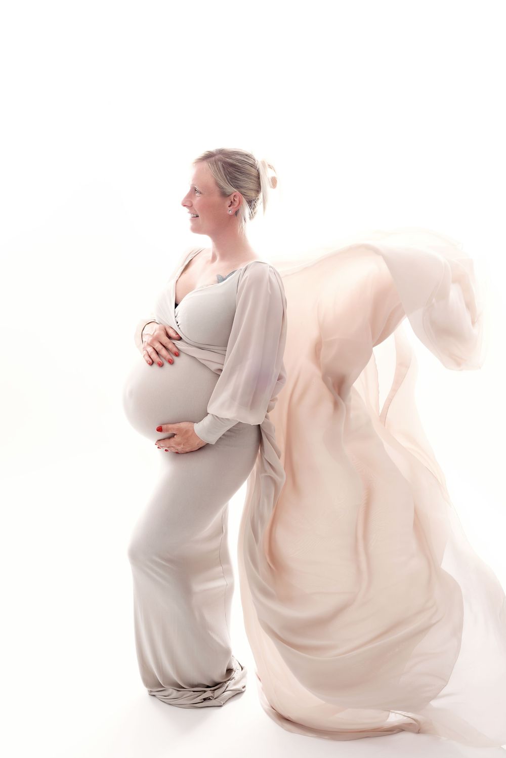Artistic maternity photos with flowing fabric and soft lighting creating dreamy effect.