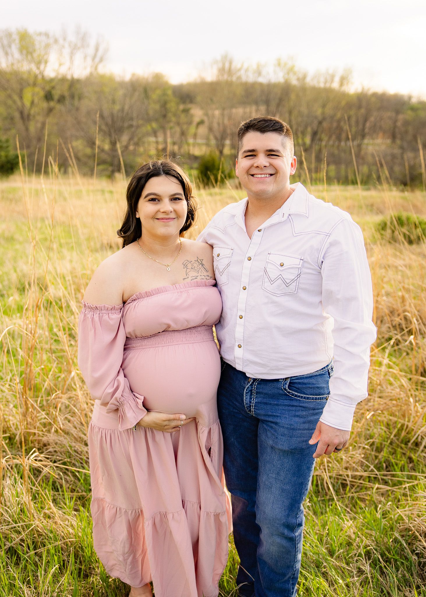 maternity photos of couple of expecting mother in field with husband