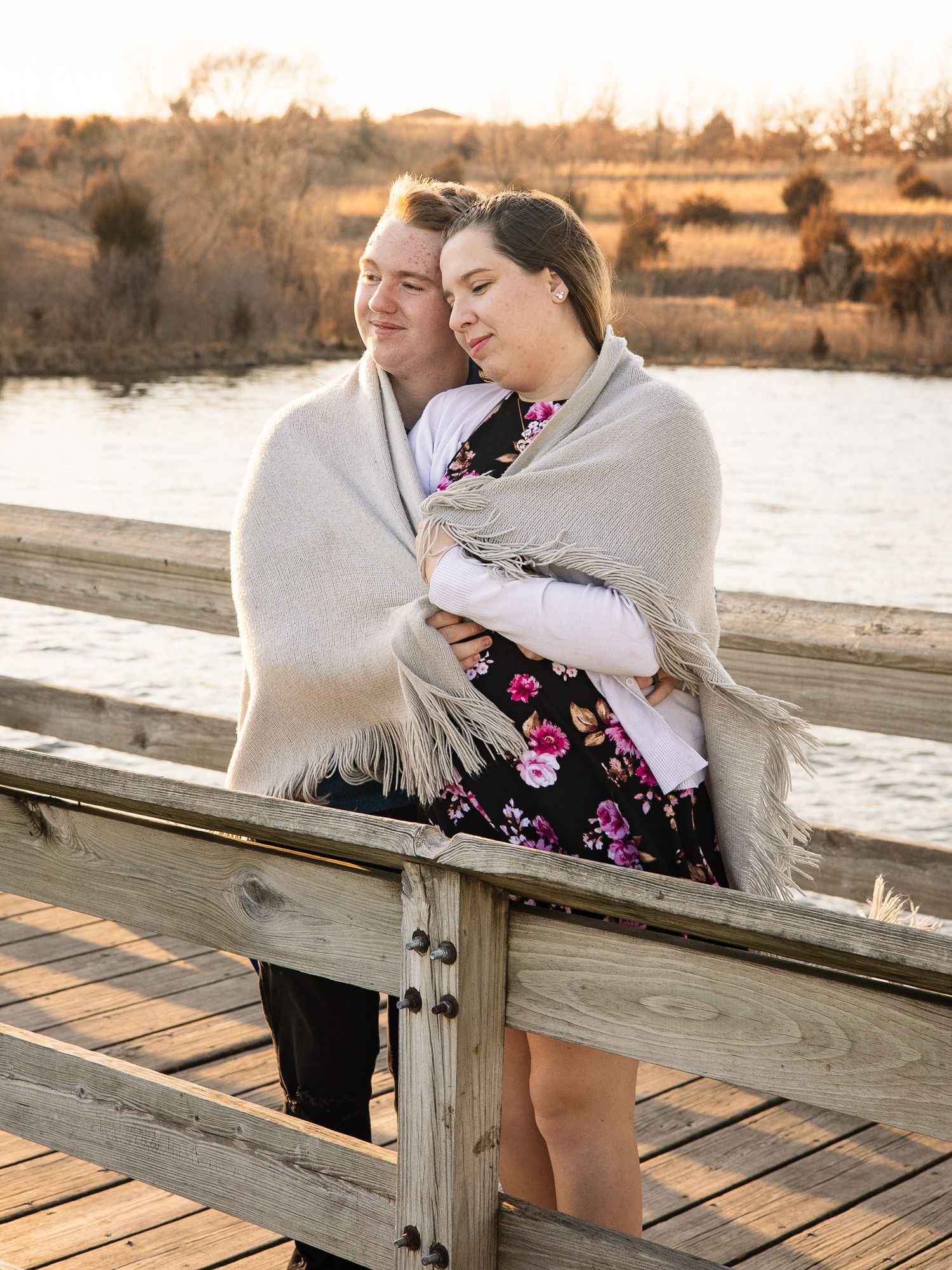 married couple posing by a lake for a gender reveal photoshoot