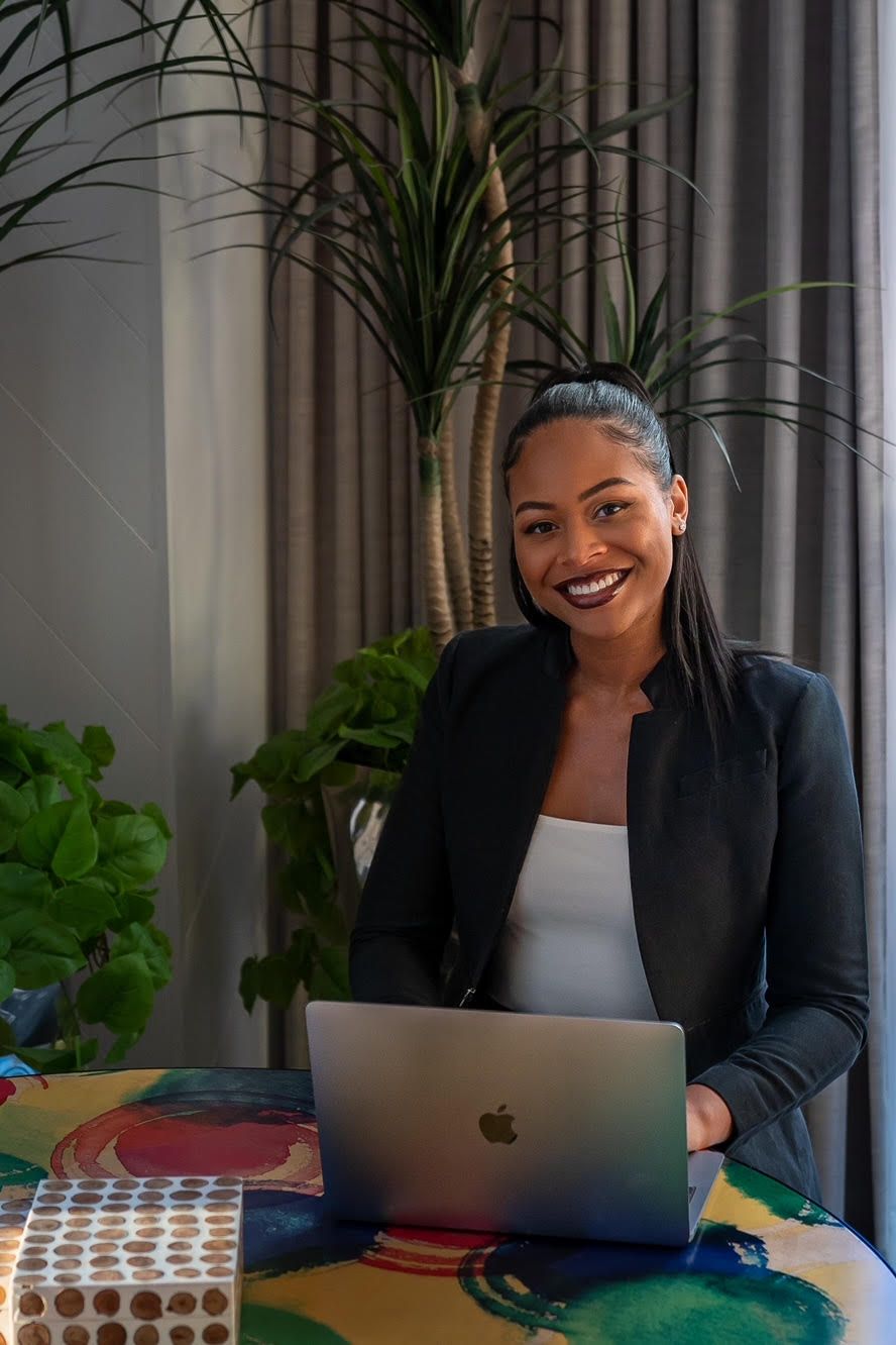 Professional working on MacBook laptop with indoor plants in background.