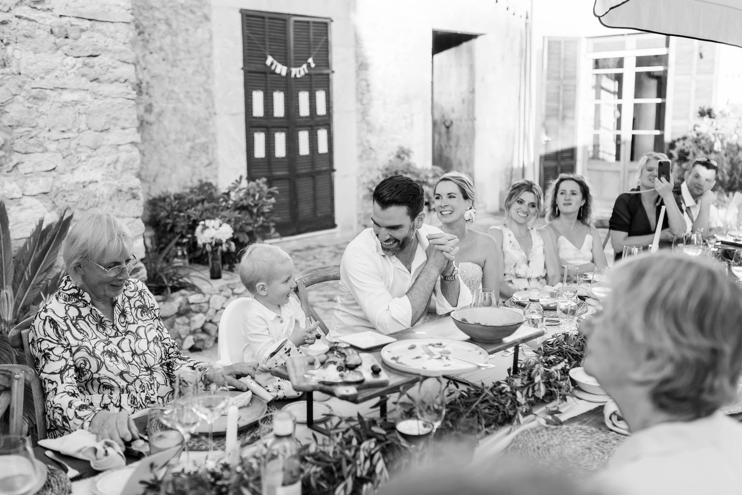 Eine Reihe von Schwarz-Weiß-Fotografien zeigt eine Hochzeitsgesellschaft, wie sie während dem Dinner Reden zuhören und Spaß haben.