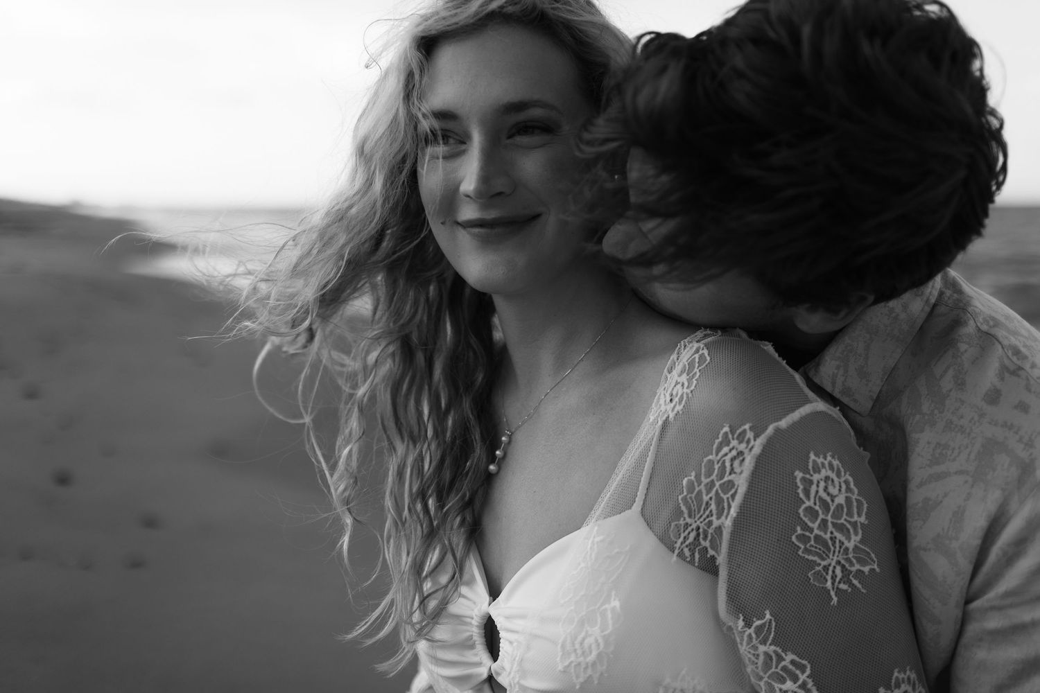 Black and white beach portraits capturing intimate moments at sunset.