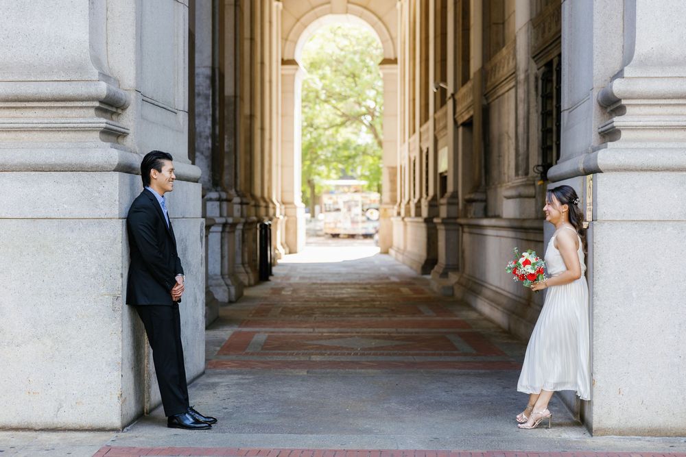 Wedding couple poses in elegant stone archway corridor for romantic bridal portraits.
