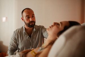 Emotional birthing moment captured in warm tones as support person offers assistance.