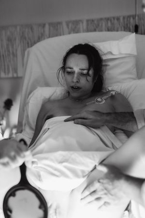 Patient lying in hospital bed with medical monitoring equipment.