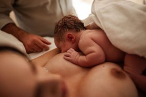 Newborn baby resting skin-to-skin on parent's chest during intimate bonding moment.
