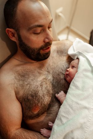 Peaceful moment of skin-to-skin bonding with newborn wrapped in soft blanket.